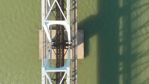 A flying camera flies over a railway bridge stretched across a river along Video stock 116113848