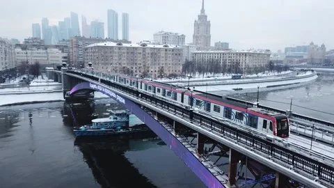 The flying camera slowly flies up to the bridge on which the metro train Video stock 169071674