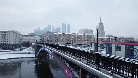 The flying camera slowly flies up to the bridge on which the metro train Stock Footage 169071755