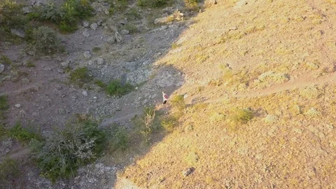 Flying camera view of young man in casual running to the top of the mountain  Stock Footage 93002707