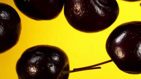 Flying cherries on a yellow background in slow motion Stock Footage 151118697