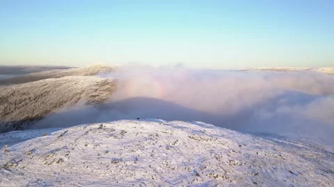 Flying in a clear sky above low clouds over a snow-covered  mountain Stock Footage 143552081