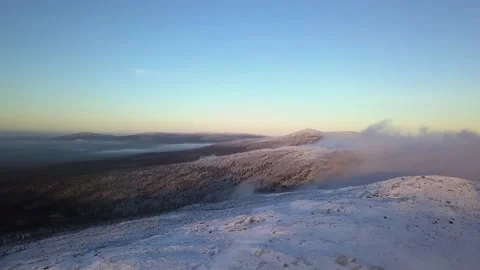 Flying in a clear sky above low clouds over a snow-covered  mountain Stock Footage 143575431
