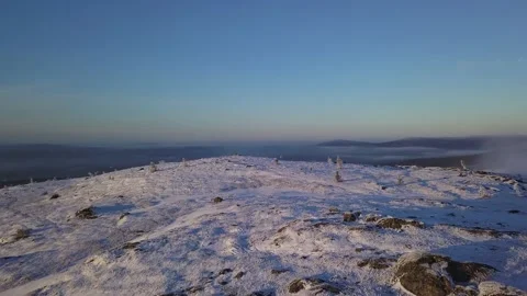 Flying in a clear sky above low clouds over a snow-covered  mountain Stock Footage 143680777
