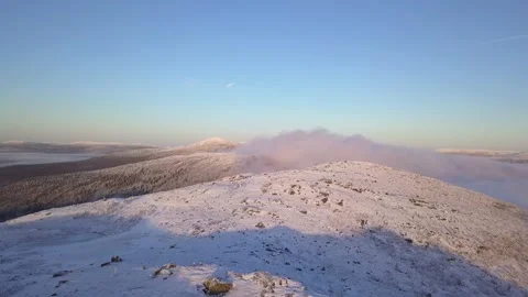 Flying in a clear sky above low clouds over a snow-covered  mountain Stock Footage 143680778