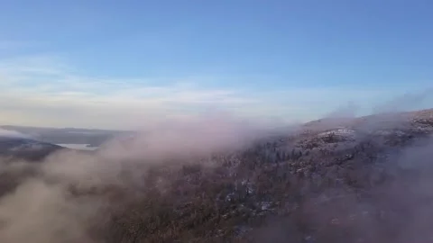 Flying in a clear sky above low clouds over a snow-covered  mountain Stock Footage 143680952