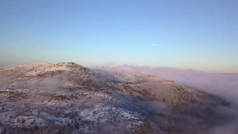 Flying in a clear sky above low clouds over a snow-covered  mountain Stock Footage 143681030