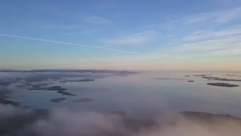 Flying in a clear sky above low clouds over a snow-covered  mountain Stock Footage 143709319