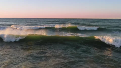 Flying close above the ocean waves at sunrise along the beach Stock Footage 143177104