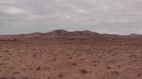 Flying close to the ground above a desert landscape with mountains Stock Footage 174902595