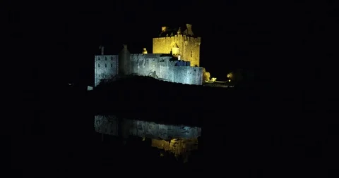 Flying close over lit up Eilean Donan Castle, Scotland at night drone aerial 4K Stock-Footage 104585049