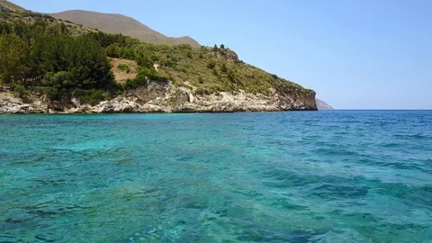Flying close to sea surface towards mountains in Italy Sicily Stock Footage 107804729