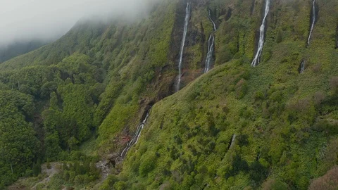 Flying in a cloud on the top of mountain with waterfall on its green steep slope Stock Footage 118016983