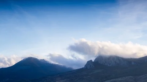 Flying clouds burst on the tops of the mountains against the blue sky Time lapse Stock Footage 98185526