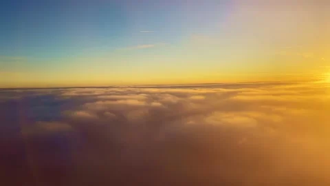 Flying into the clouds illuminated in orange by the suns rays at sunset Stock Footage 168237124