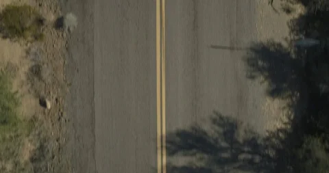 Flying directly overhead of a straight desert road with cracked asphalt Stock Footage 99059184
