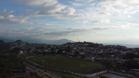 Flying with a dji mini 2 drone through a sports field until arriving at a town Stock Footage 236173694