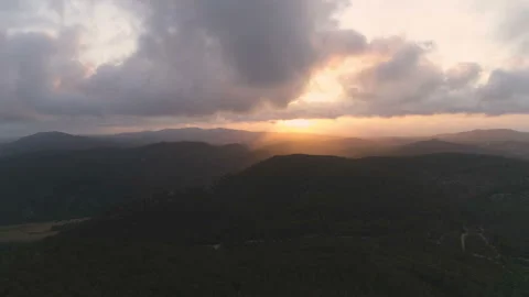 Flying down to the dark mountain forest. View of clouds and golden hour sunset Video stock 108107046
