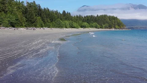 Flying down a deserted beach with smokey mountains in the distance, 4K Stock Footage 124979023