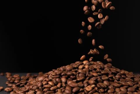 Flying down falling brown coffee beans on black background Stock Photos