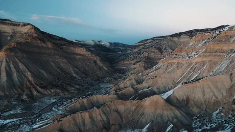 Flying into dramatic desert mountain canyon with a fresh layer of snow at sunset Stock Footage 124821639