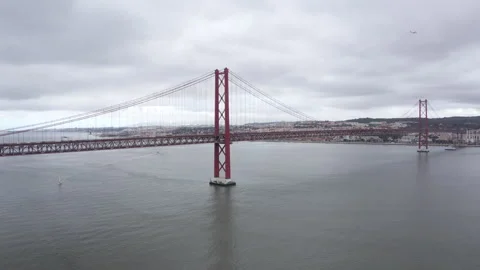 Flying drone 4K video of 25 de Abril suspension Bridge steel red construction ov Video stock 308723609