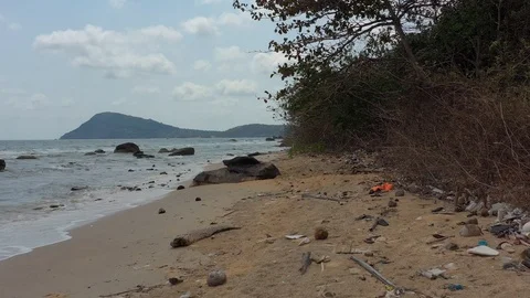 Flying by drone above garbage trash on a beach shore plastic next to sea waves o Stock Footage 124603649