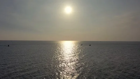 Flying by drone against sunset above ocean water towards two boats crossing Stock Footage 124106882