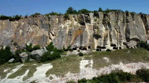 Flying a drone along a mountain with a cave city Stock Footage 160855181