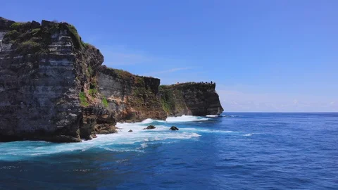Flying on a drone along the steep cliffs above the waves of the ocean. Stock Footage 127589730
