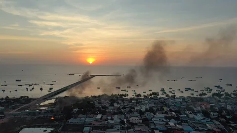 Flying by drone behind smoke cloud above fishing village old town in front of se Stock Footage 124366143