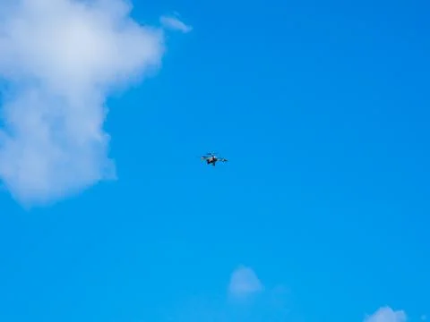 Flying drone on blue sky background. The drone is being controlled to stay .. 写真素材