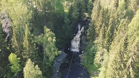 Flying the drone from the bottom up between the trees towards the waterfall Vidéo 161824573