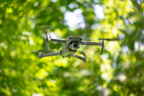 Flying drone with camera hovering inside a forrest, natural background Stock Photos