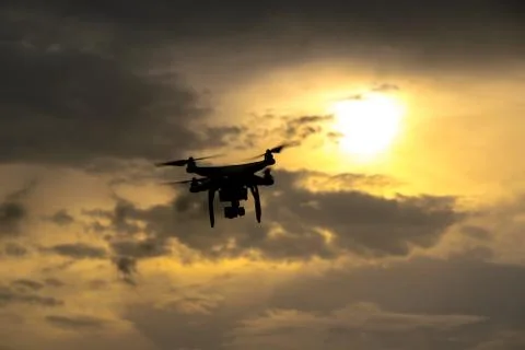 Flying drone with camera on the sky at sunset Stock Photos