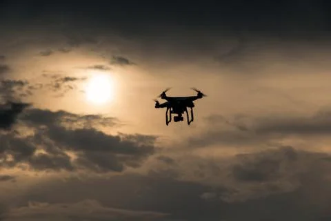 Flying drone with camera on the sky at sunset Stock Photos