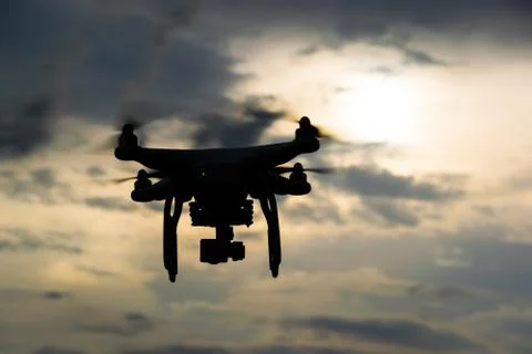 Flying drone with camera on the sky at sunset Stock Photos