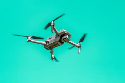 Flying drone with camera on turquoise background with copy space. Stock Photos