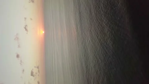 A flying drone captures the sunset at sea level (vertical video). Stock Footage 155998979