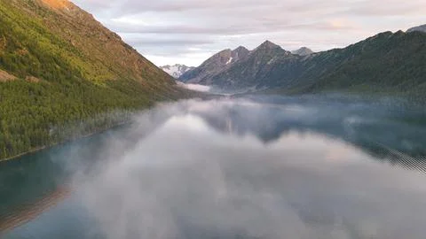 Flying a drone in the clouds over the Multinsky mountain lake in Altai Stock Photos