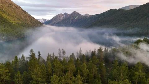 Flying a drone in the clouds over the Multinsky mountain lake in Altai Stock Photos