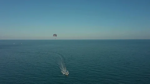 Flying by drone in front of boat pulling parachute following it from behind abov Stock Footage 124416493