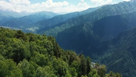 Flying drone from green forest mountain peak and getting a aerial view of valley Stock Footage 254413878