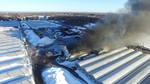 Flying drone making 180 degree turn to show burning warehouse in winter Stock Footage 103457240