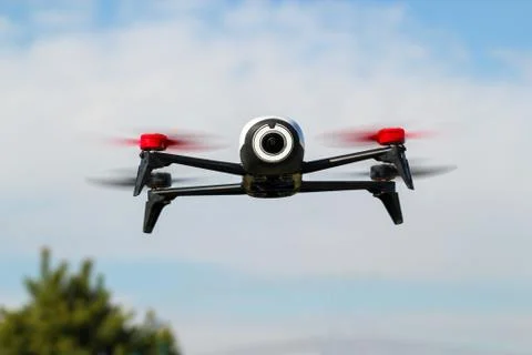 Flying drone with mounted camera in the blue cloudy sky. Stock Photos