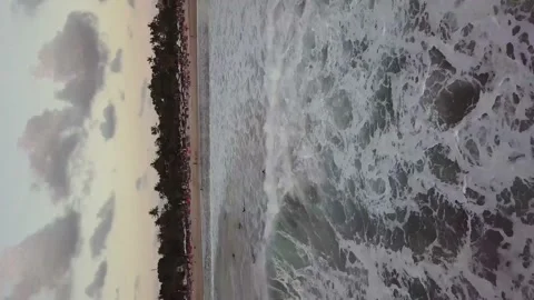A flying drone moves away from the coast and captures the sea. (vertical video) Stock Footage 155998933