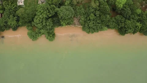 Flying a drone over a beach with blue water and yellow sand, top view Stock Footage 134016893