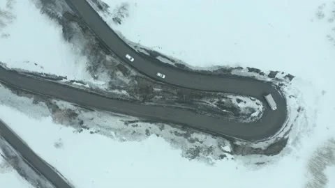 Flying on drone over a bend of a mountain road, along which a string of cars is  Stock Footage 236395953