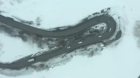 Flying on drone over a bend of a mountain road, along which a string of cars is  Stock Footage 236396634