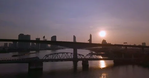 Flying with drone over bridge filled with traffic against sun in sunrise Stock Footage 108644668